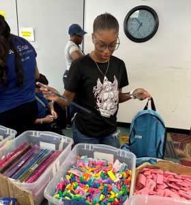 A girl sorting colorful beads and craft supplies at a table.