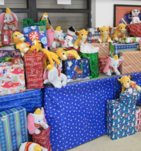 A pile of colorfully wrapped presents with stuffed animals on top.